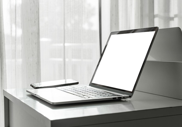 Computador portátil com tela em branco e smartphone na mesa branca no interior da casa ou fundo do escritório