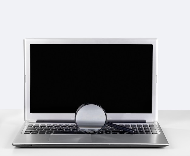 Computador portátil com vidro de ampliação isolado no fundo