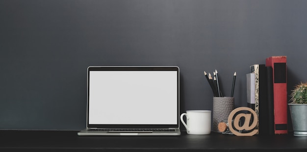 Computador portátil de tela em branco aberto no espaço de trabalho moderno com decorações e material de escritório