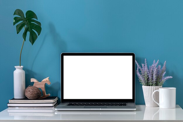 Computador portátil de tela em branco de maquete na mesa superior branca e parede azul clara.