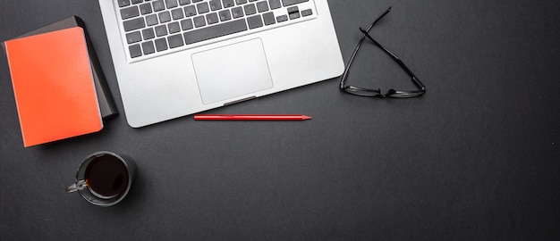 Computador portátil e telefone celular no banner de mesa de escritório de cor preta