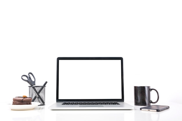 Computador portátil; xícara de café; telefone móvel e bolo no fundo branco