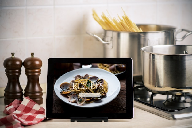 Computador tablet de receitas de comida na mesa de madeira rústica. macarrão espaguete com amêijoas