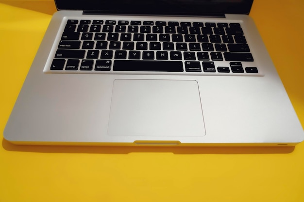 Computadora de aluminio moderna o teclado portátil aislado fondo amarillo