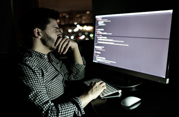 Computadora desarrolladora de software en la oscura oficina en casa