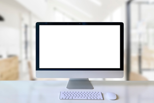 Computadora de escritorio moderna de la maqueta con la pantalla blanca en blanco en la tabla de madera blanca en sitio del espacio de trabajo.