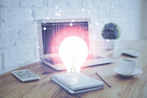 Computadora de escritorio en la oficina con holograma de icono de bombilla Exposición múltiple Concepto de idea
