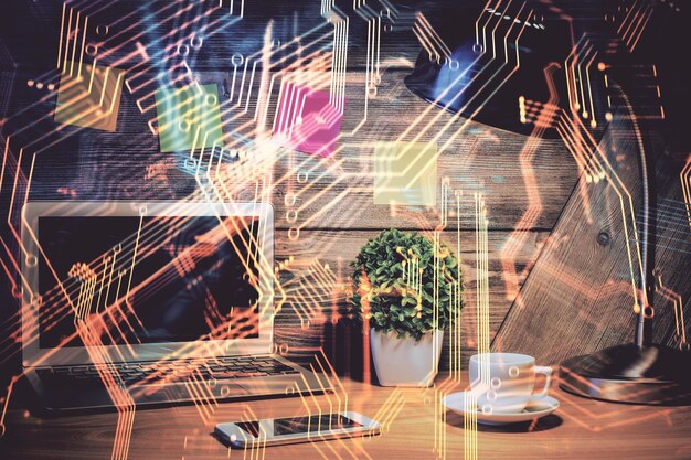 Computadora en el escritorio en la oficina con holograma de tema tecnológico Doble exposición Concepto tecnológico