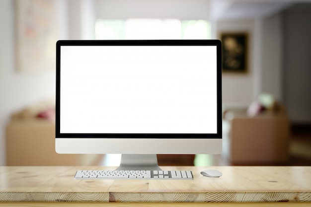 Foto computadora de escritorio de la pantalla en blanco de la maqueta en la tabla de madera del escritorio sobre sala de estar.