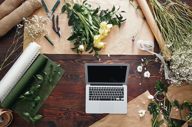 Foto computadora y flores en el escritorio.