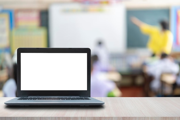 Computadora en la mesa imagen borrosa del aula de los niños como fondo