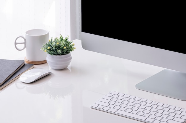 Computadora con pantalla en blanco y planta de interior