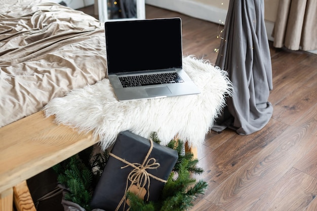 Computadora portátil. árbol de navidad y regalos en el fondo.