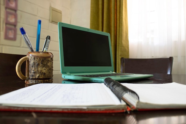 Una computadora portátil y un bolígrafo en un escritorio con una computadora portátil verde