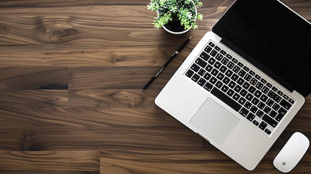 una computadora portátil con un bolígrafo y una planta en una mesa de madera