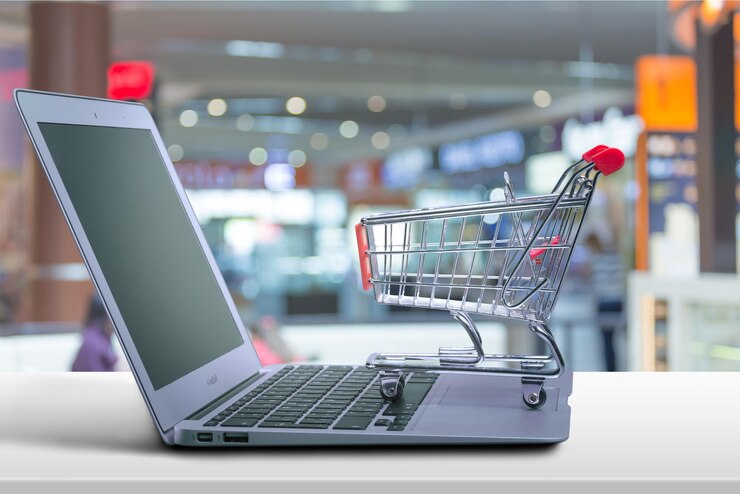 Foto computadora portátil y carrito de compras en el fondo de la playa