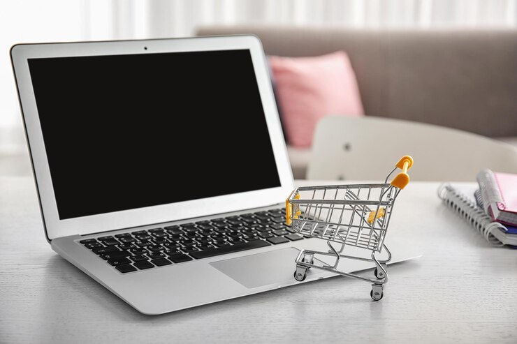 Foto computadora portátil y carrito de compras pequeño en la mesa concepto de compras por internet