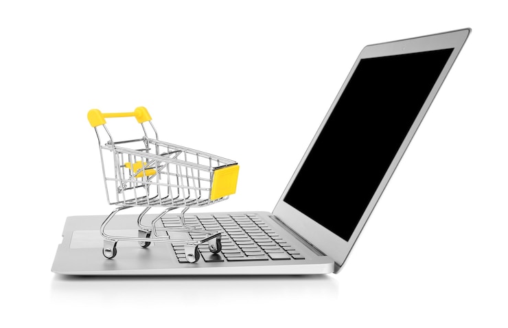 Foto computadora portátil y carrito de compras pequeño sobre fondo blanco concepto de compras por internet