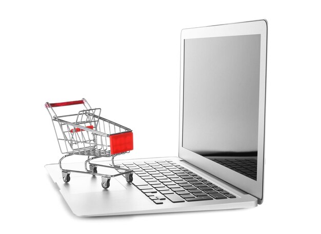 Computadora portátil y carrito pequeño sobre fondo blanco Concepto de compras por Internet