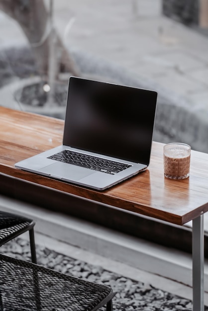 Computadora portátil y una copa de café en una cafetería con tono gris