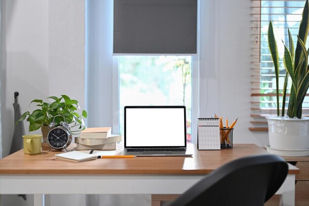 Computadora portátil despertador planta en maceta y taza de café en la mesa de madera