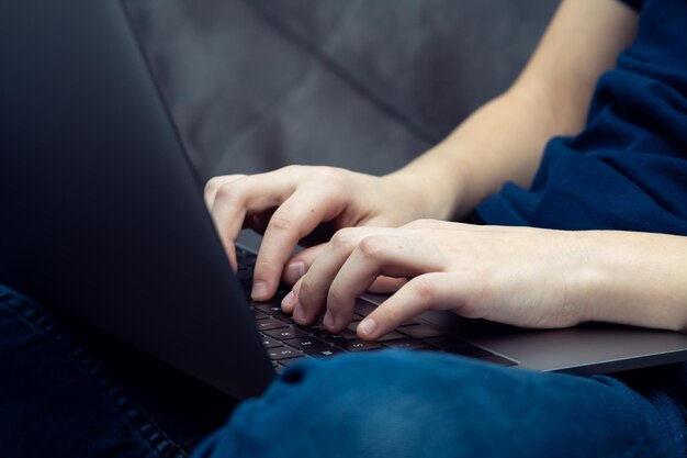 Computadora portátil digital en primer plano de piernas masculinas Hombre de negocios joven escribiendo en el teclado del portátil portátil moderno