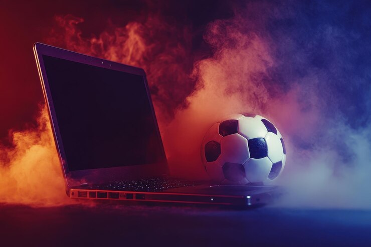 Una computadora portátil está en una mesa con una pelota de fútbol a su lado.
