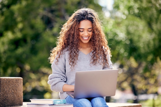 Computadora portátil de estudiante y mujer con libros en el parque al aire libre para investigación educativa o estudio Mujer africana feliz en la universidad o campus universitario en la naturaleza con tecnología para conocimiento Internet o aprendizaje