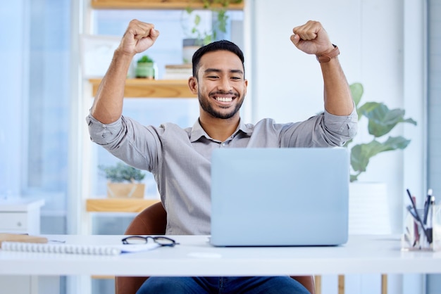 Computadora portátil de hombre de negocios y celebrar el éxito o ganar en el escritorio con el puño para un acuerdo de bonificación Hombre o empresario asiático emocionado con competencia tecnológica para obtener ganancias o logros en línea y notificación de préstamo