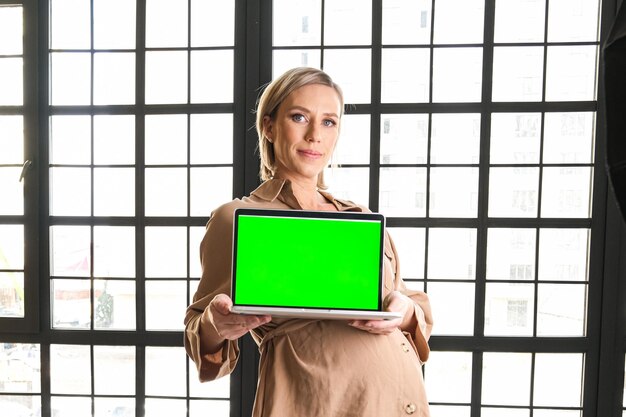 Una computadora portátil con una imagen de pantalla verde en la que una niña embarazada