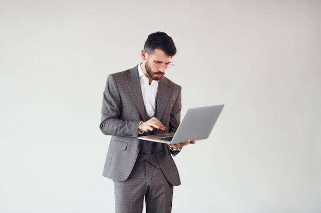 Con la computadora portátil en las manos Joven hombre de negocios con estilo en traje interior Concepción del éxito