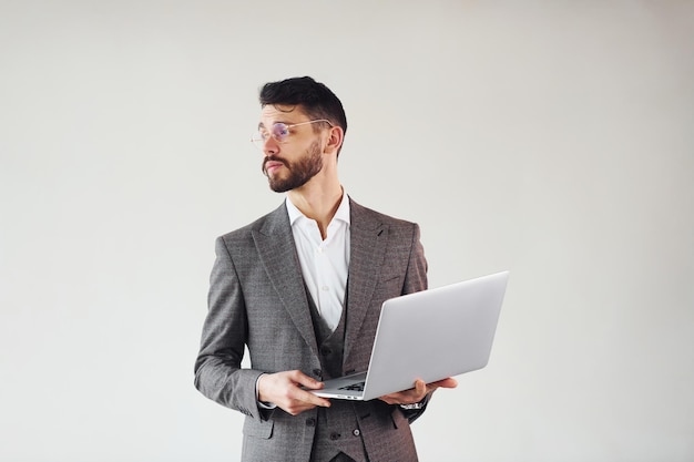 Con la computadora portátil en las manos Joven hombre de negocios con estilo en traje interior Concepción del éxito