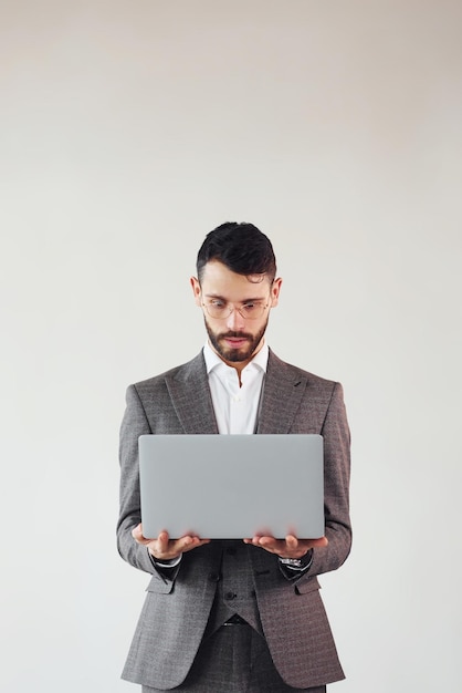 Con la computadora portátil en las manos Joven hombre de negocios con estilo en traje interior Concepción del éxito