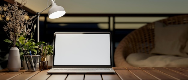 Una computadora portátil con una maqueta de pantalla blanca en una mesa de madera en un balcón
