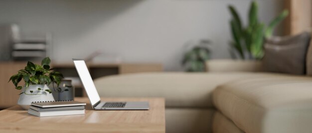 Una computadora portátil en una mesa de café de madera en una vista lateral de la sala de estar moderna y cómoda