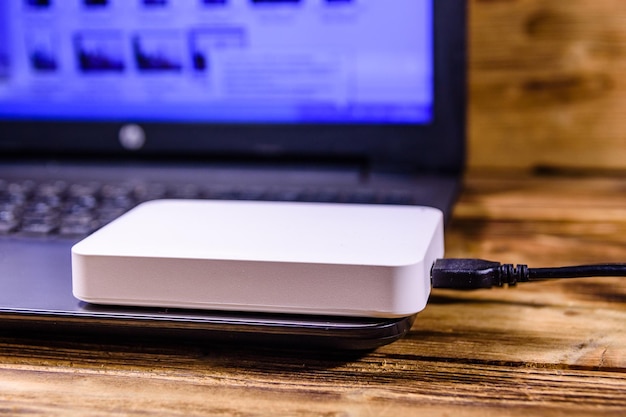 Computadora portátil moderna y disco duro ssd en un escritorio de madera