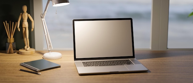 Computadora portátil moderna en una mesa de madera bajo las luces de la lámpara de mesa en un cómodo espacio de trabajo en el hogar