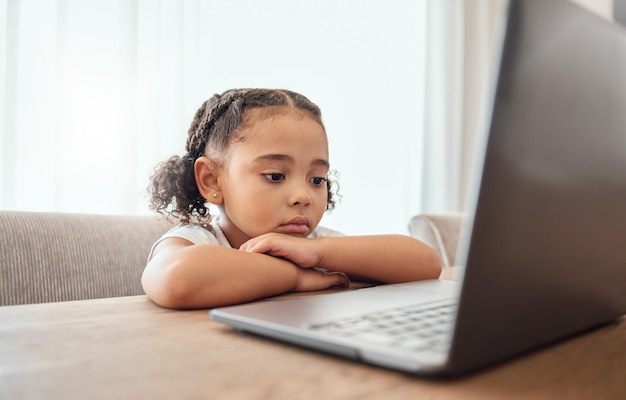 Computadora portátil para niños y educación con una niña que aprende desde casa en línea para el crecimiento o el desarrollo Computadora internet y estudio con una niña que aprende a distancia en una mesa de comedor en la casa