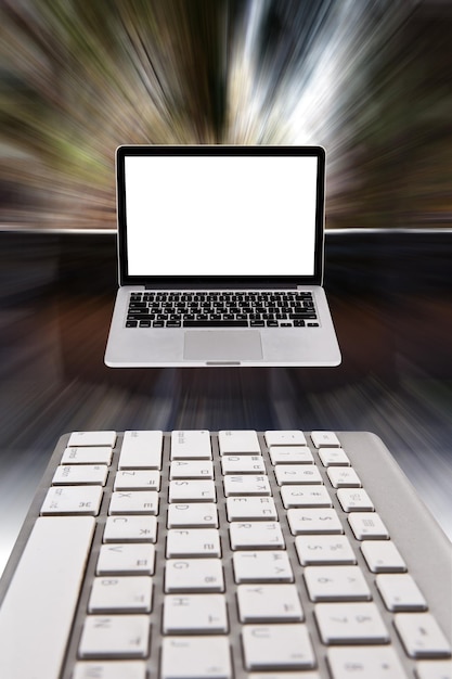 Una computadora portátil con una pantalla blanca está encima de un teclado.