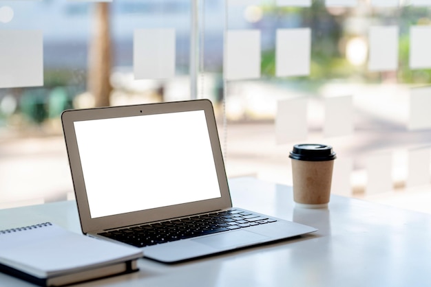 Computadora portátil con pantalla en blanco en blanco en la mesa en la maqueta de la oficina