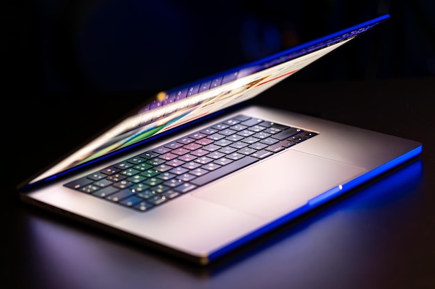 Una computadora portátil con una pantalla medio abierta en un fondo oscuro