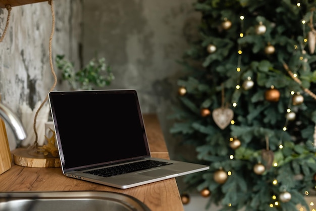 Computadora portátil. Árbol de Navidad y regalos en el fondo.