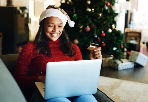 Computadora portátil con tarjeta de crédito y mujer comprando en línea el día de Navidad en la sala Fintech vacaciones de Navidad y mujer feliz de la India en una tienda virtual de computadoras o en una tienda de Internet comprando regalos o regalos