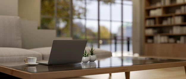 Una computadora portátil, una taza de café y plantas de decoración en una mesa de café en una sala de estar contemporánea