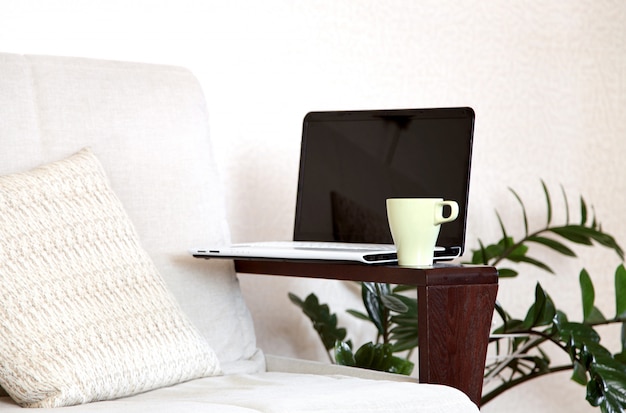Una computadora portátil y una taza de té en el sofá. Oficina en casa.