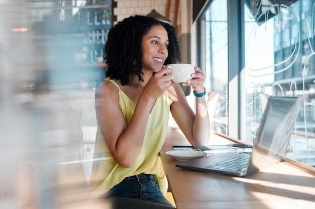 Computadora portátil de ventana y cafetería con una bloguera negra bebiendo una bebida durante el trabajo remoto Cibercafé independiente y puesta en marcha con una atractiva joven que trabaja en un restaurante