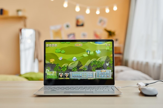 Computadora portátil con videojuego en pantalla parada en el escritorio frente a la cámara
