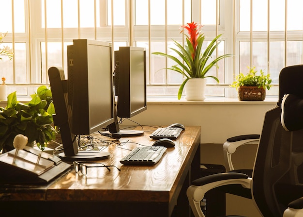 Computadores na mesa ao lado da janela do escritório