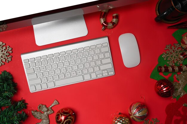 Computer auf rotem Hintergrund mit Weihnachtsschmuck.