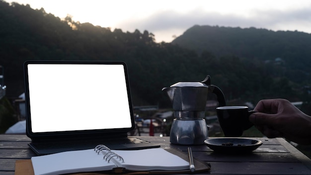Computer-Laptop-Notebook und Kaffeetasse auf Holztisch mit Blick auf die Naturberge
